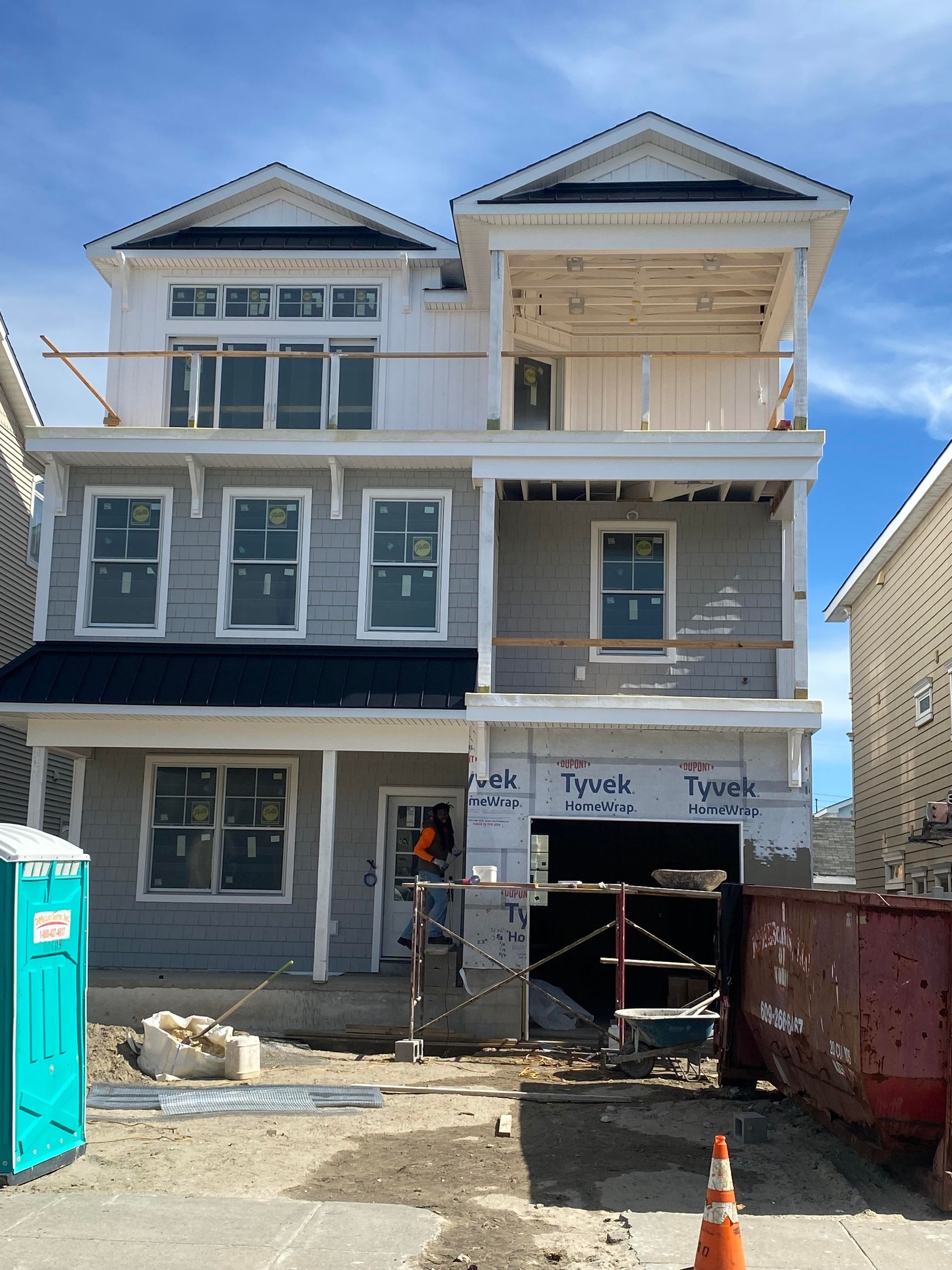 A house under construction with a blue portable toilet in front of it