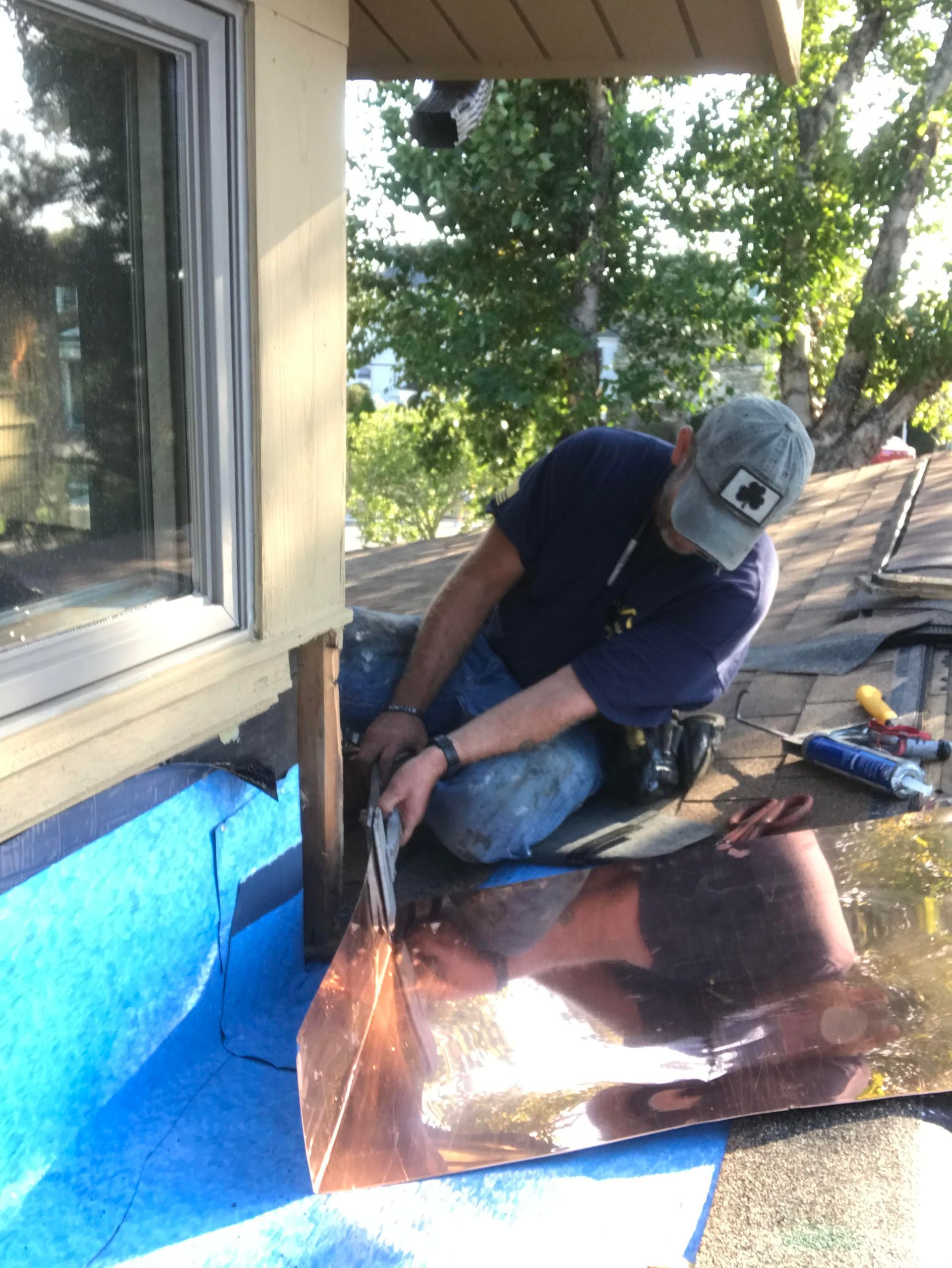 A man wearing a hat with the letter c on it is working on a roof