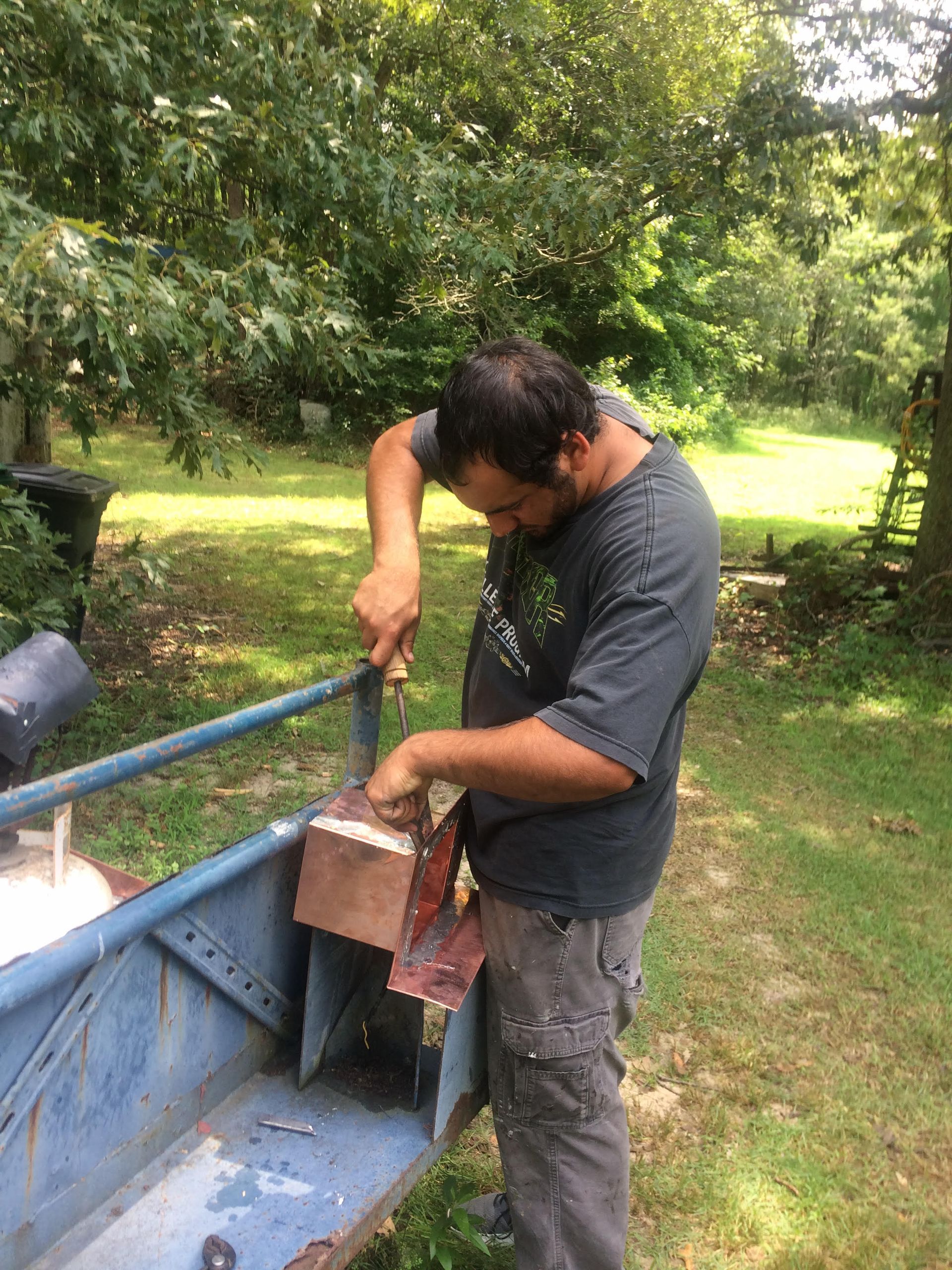A man is working on a boat in a yard.
