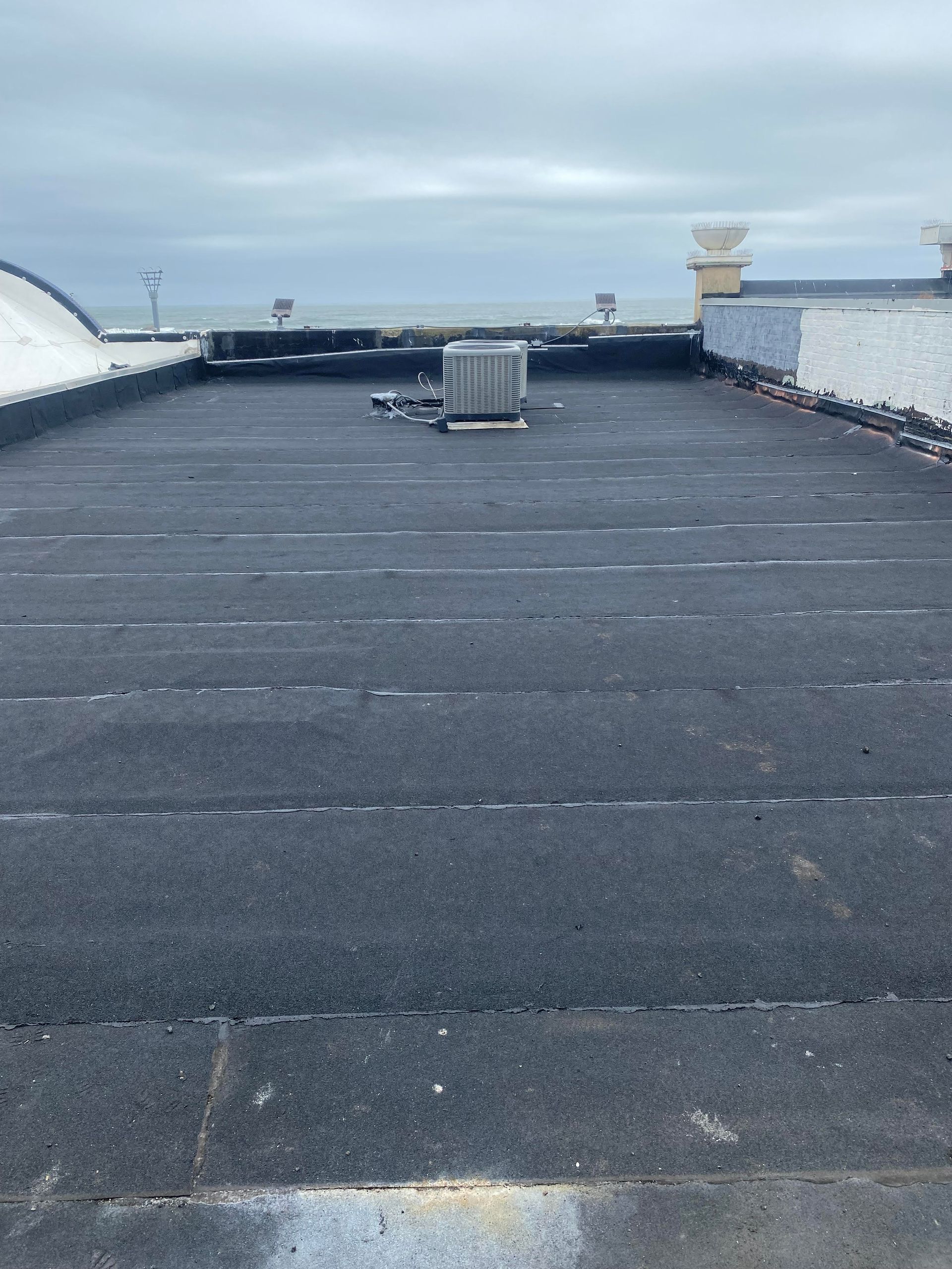 The roof of a building with a black roof and a gray sky in the background.