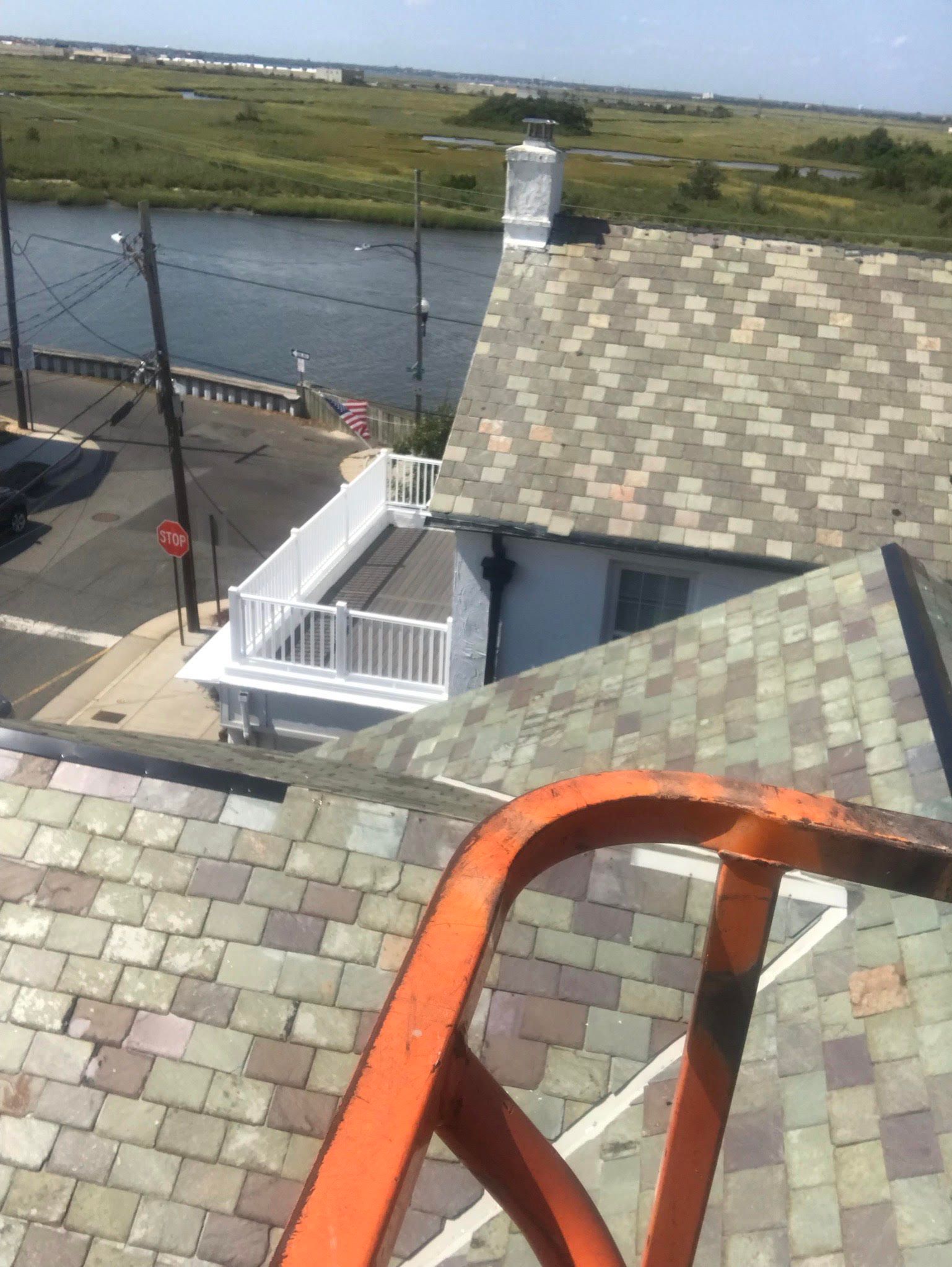A ladder is sitting on top of a roof overlooking a river.