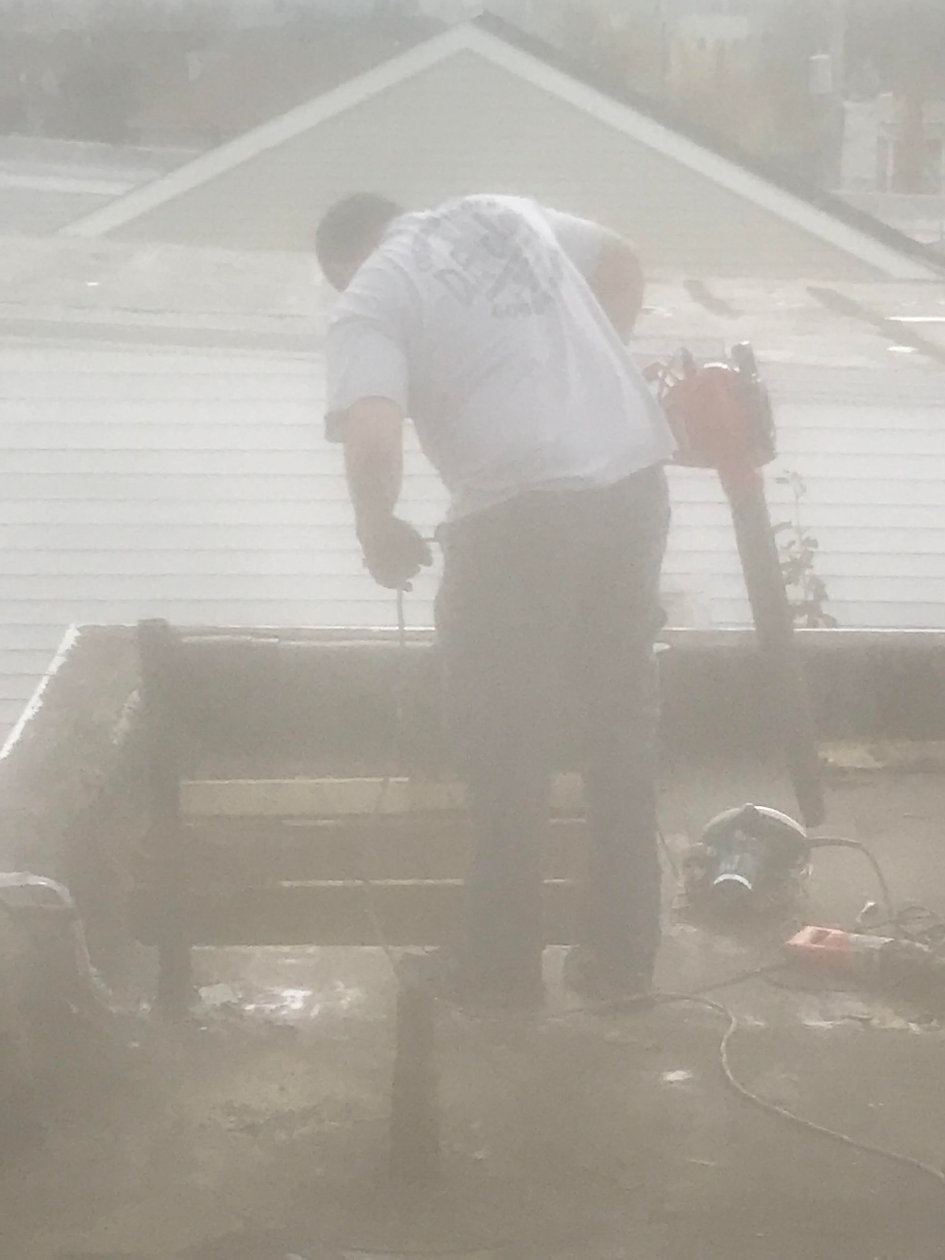 A man is working on a roof in the fog.