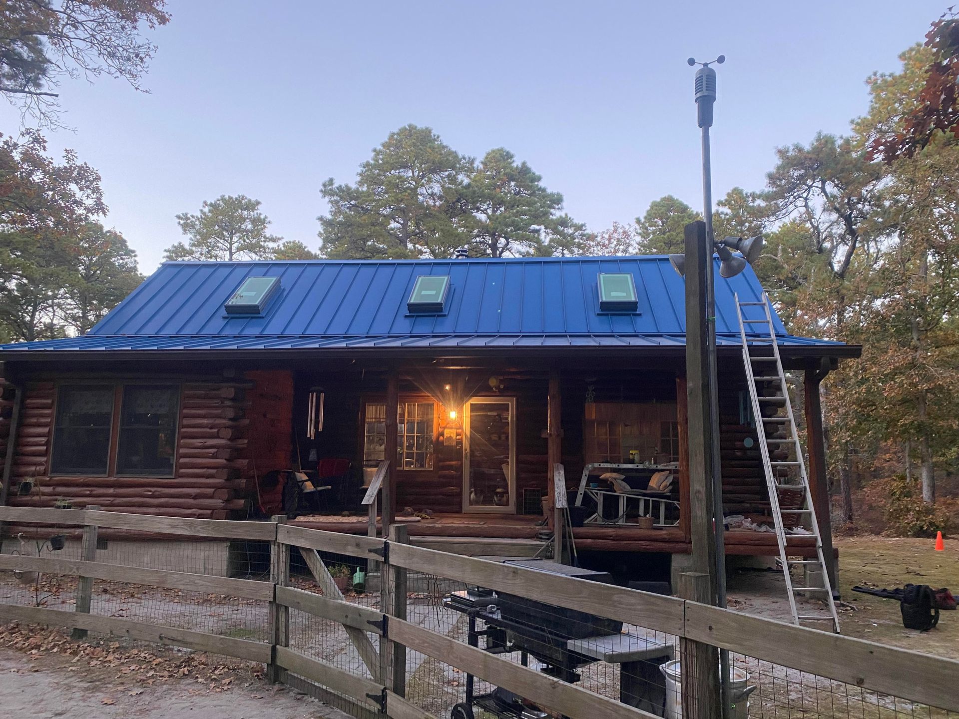A blue roof is being painted on a log cabin.