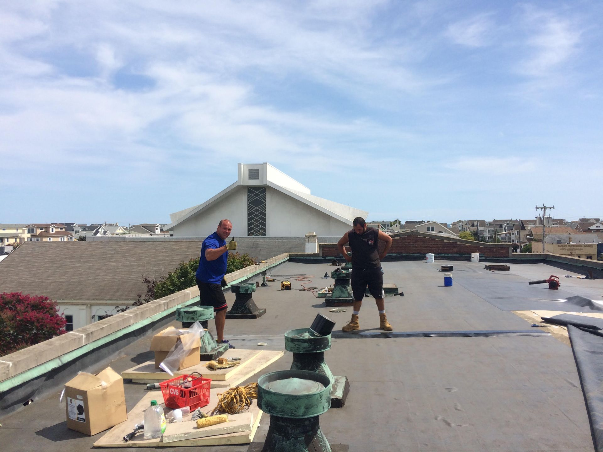 Two men are standing on the roof of a building.