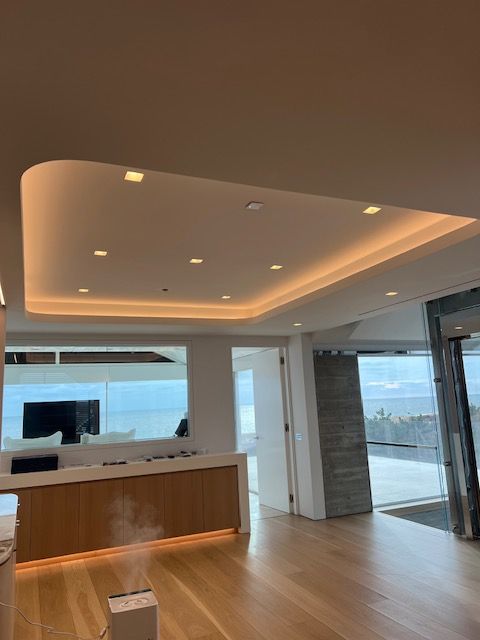 Modern office interior with recessed ceiling lighting, wood floors, and floor-to-ceiling windows.
