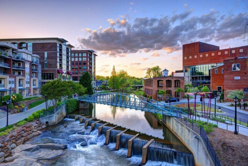Scenic view of downtown Greenville, SC at sunset featuring Falls Park bridge, and Reedy River