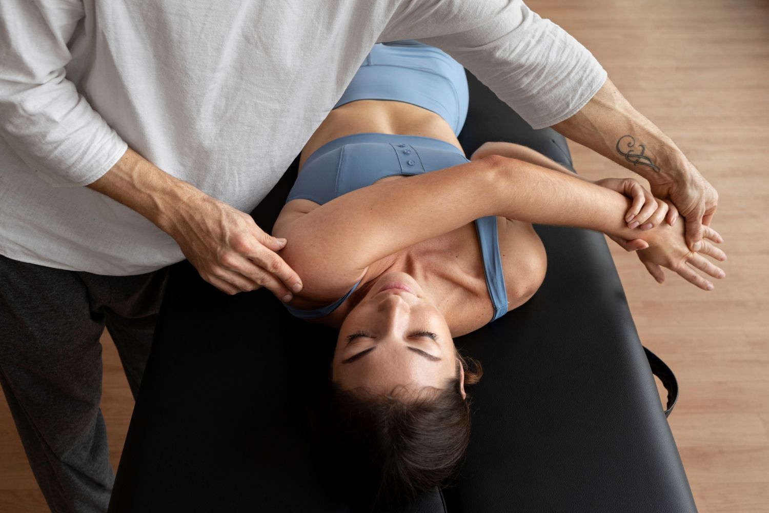 A woman is laying on a table getting a massage from a man.