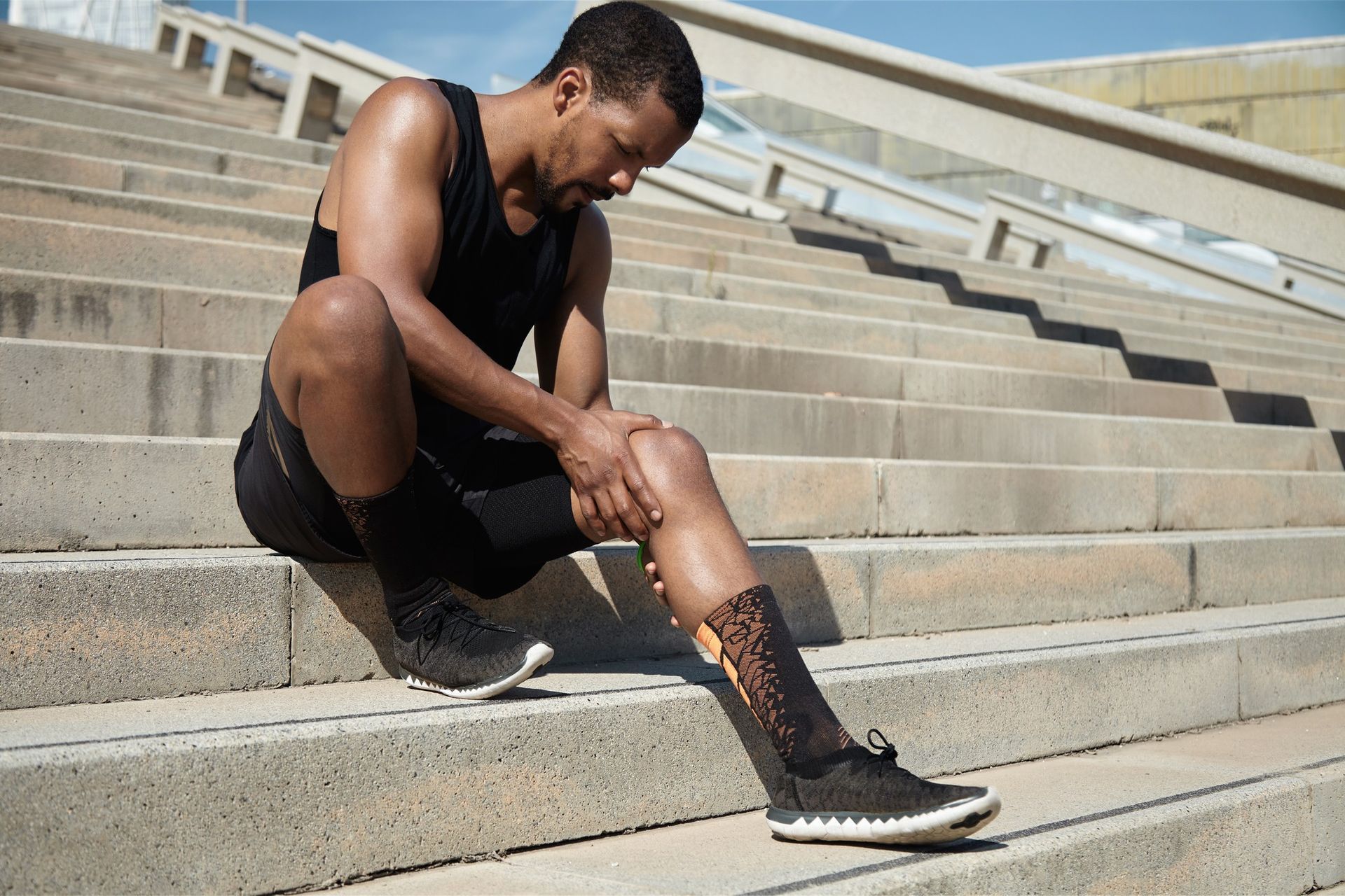 A man is sitting on a set of stairs holding his knee.