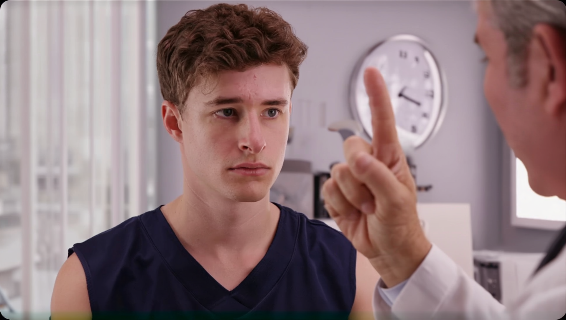 A doctor is examining a young man 's eye in a hospital.