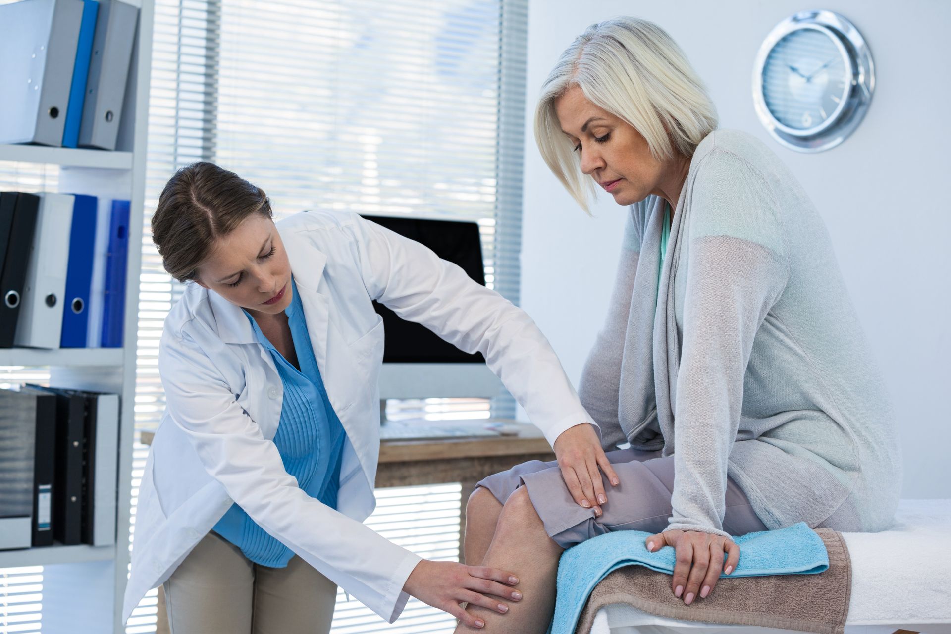 A doctor is examining a patient 's knee in a hospital.