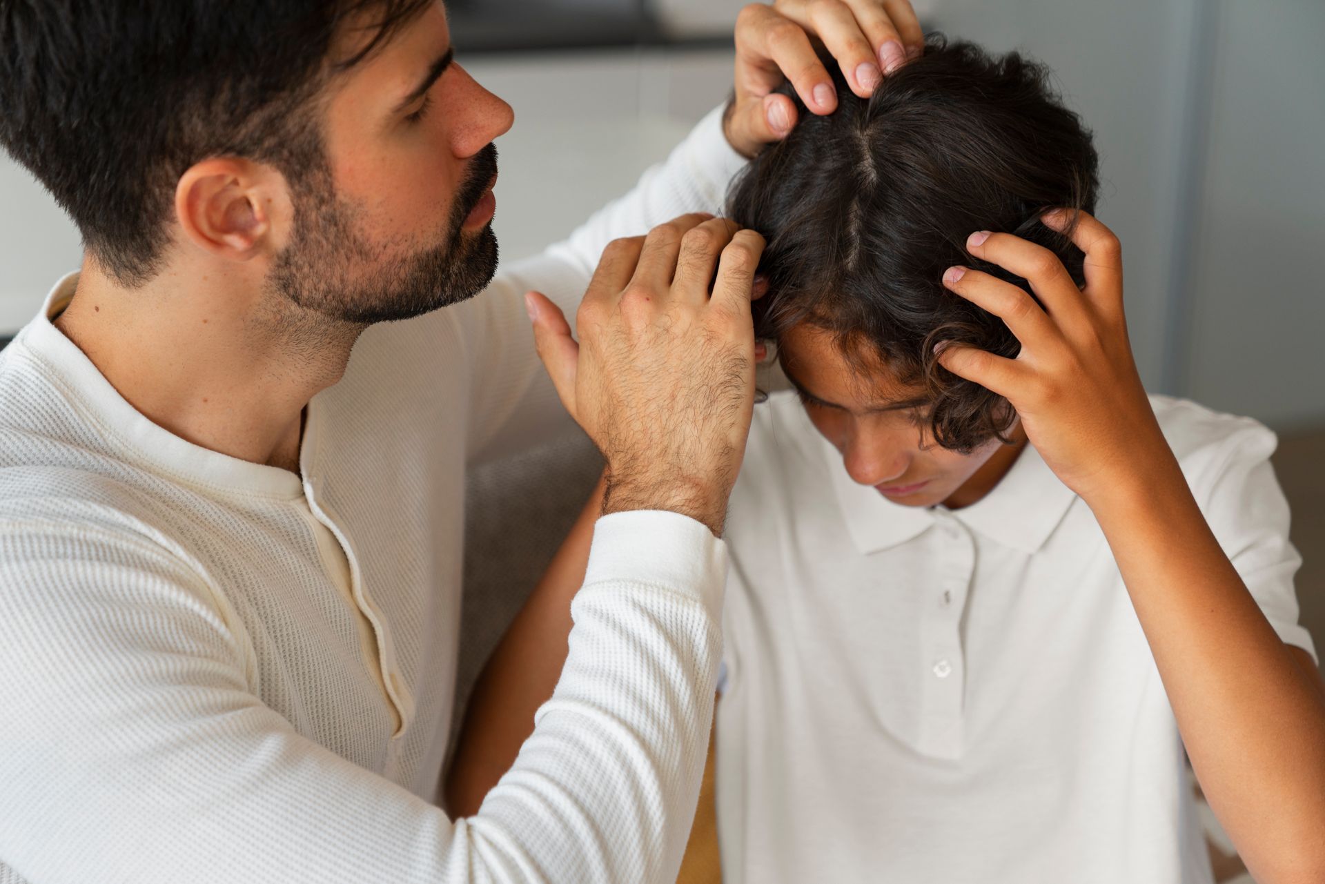 a man checking a kid's head for injury