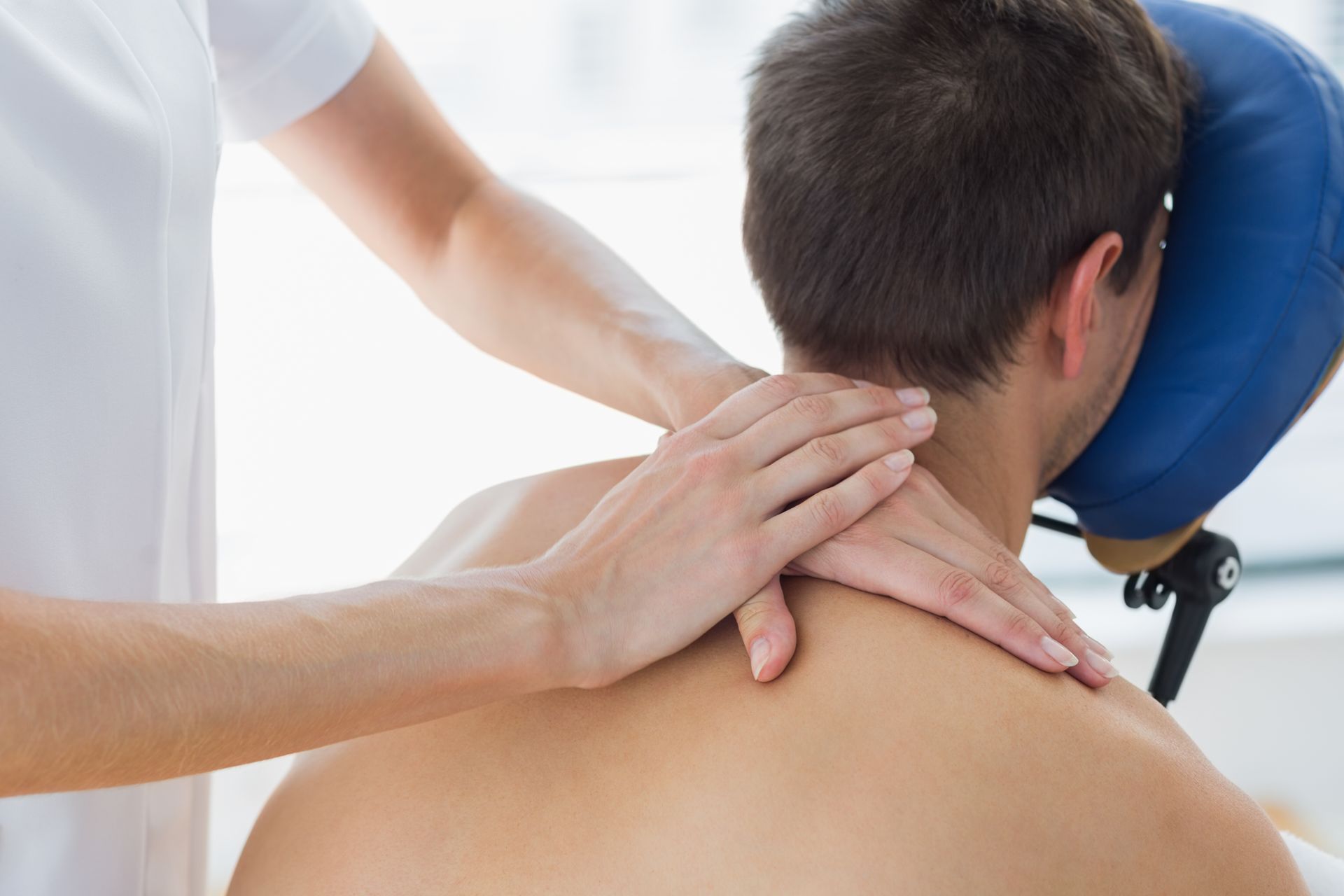 A man is getting a massage from a woman in a chair.