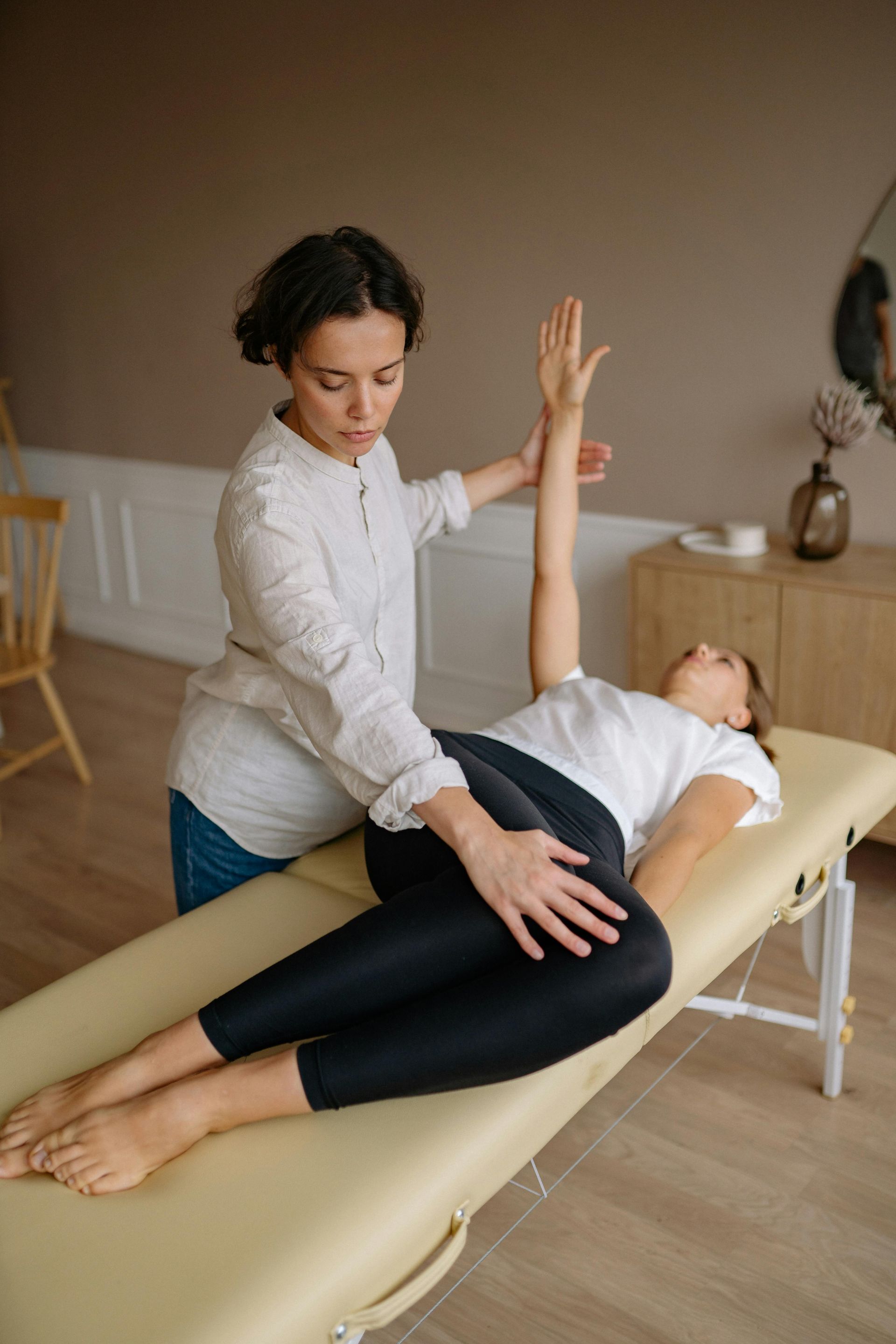 A woman is laying on a table getting a massage from a woman.