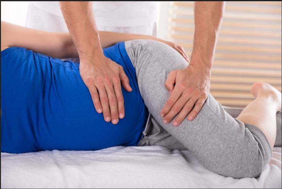 A pregnant woman is getting a massage from a man.