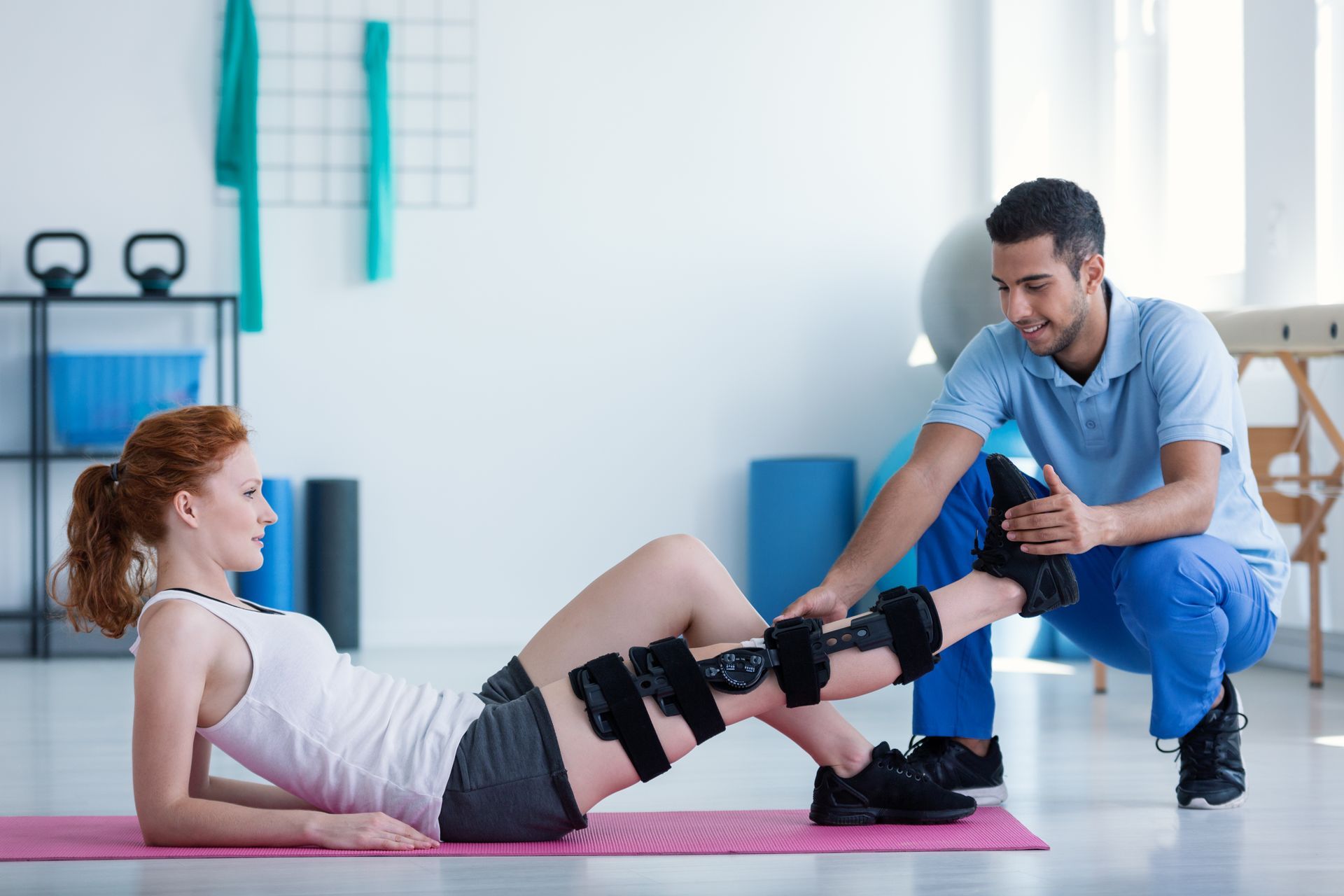 A man is helping a woman with a knee brace on her leg.