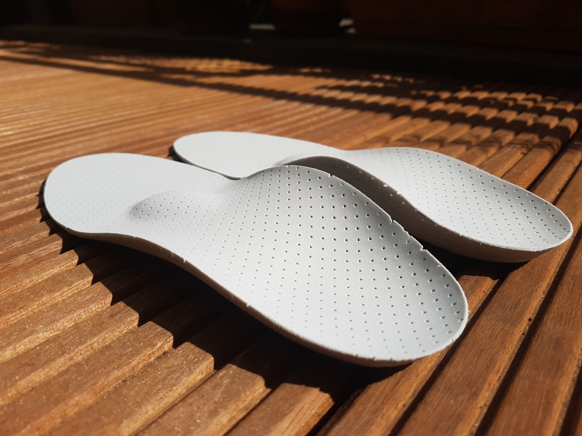 A pair of white insoles are sitting on a wooden surface