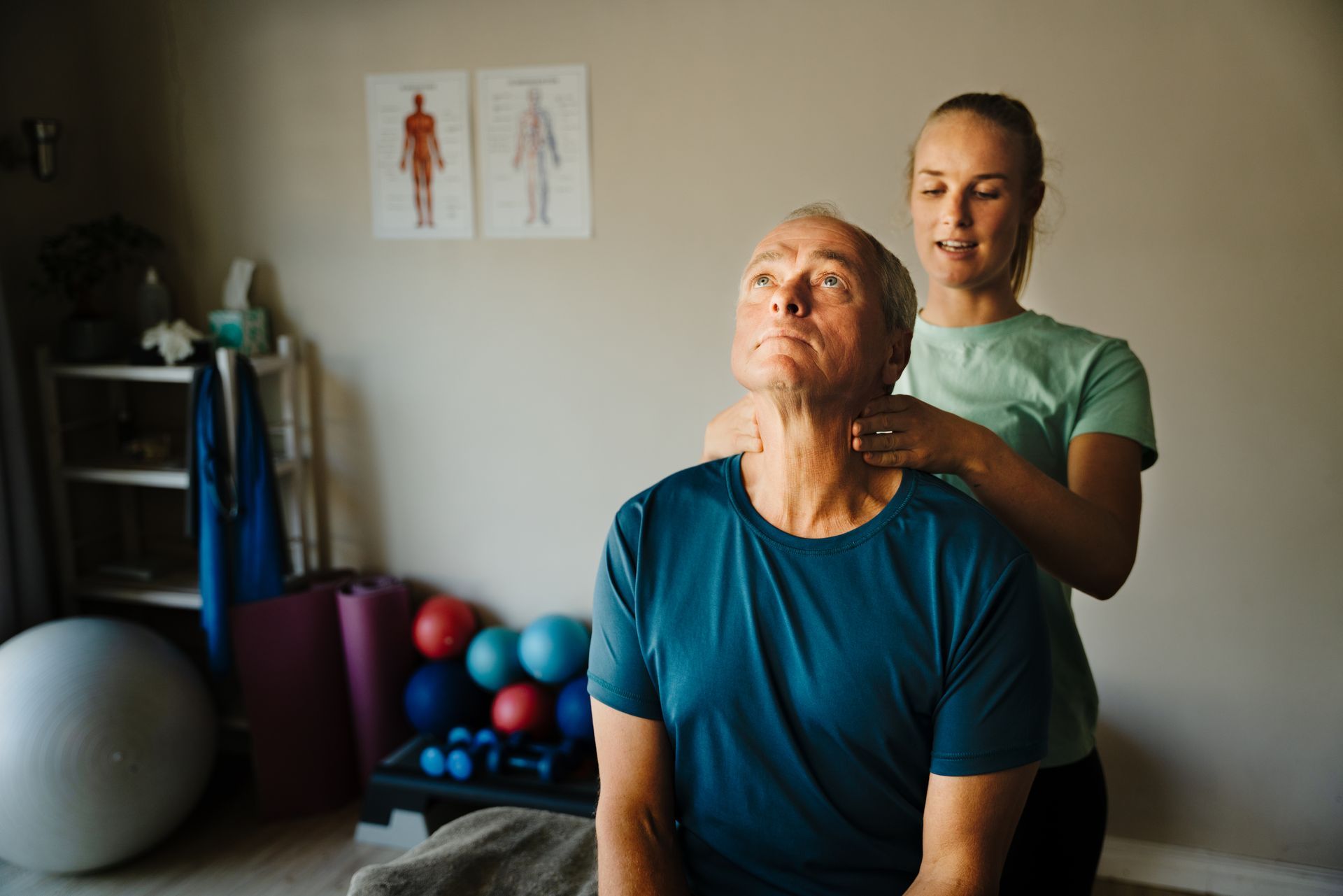 A woman is giving an older man a massage in a gym.