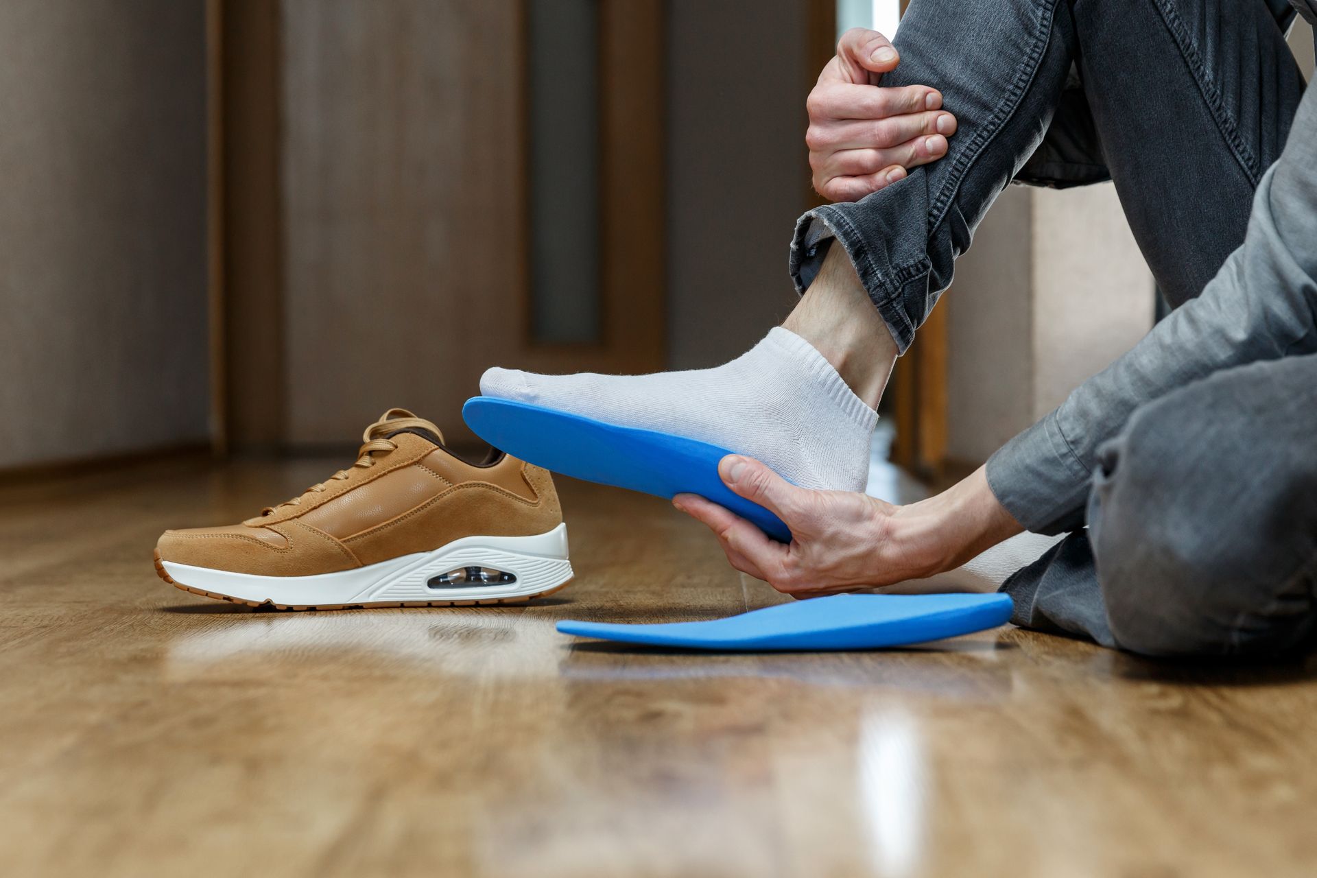 A person is sitting on the floor putting insoles on their feet.