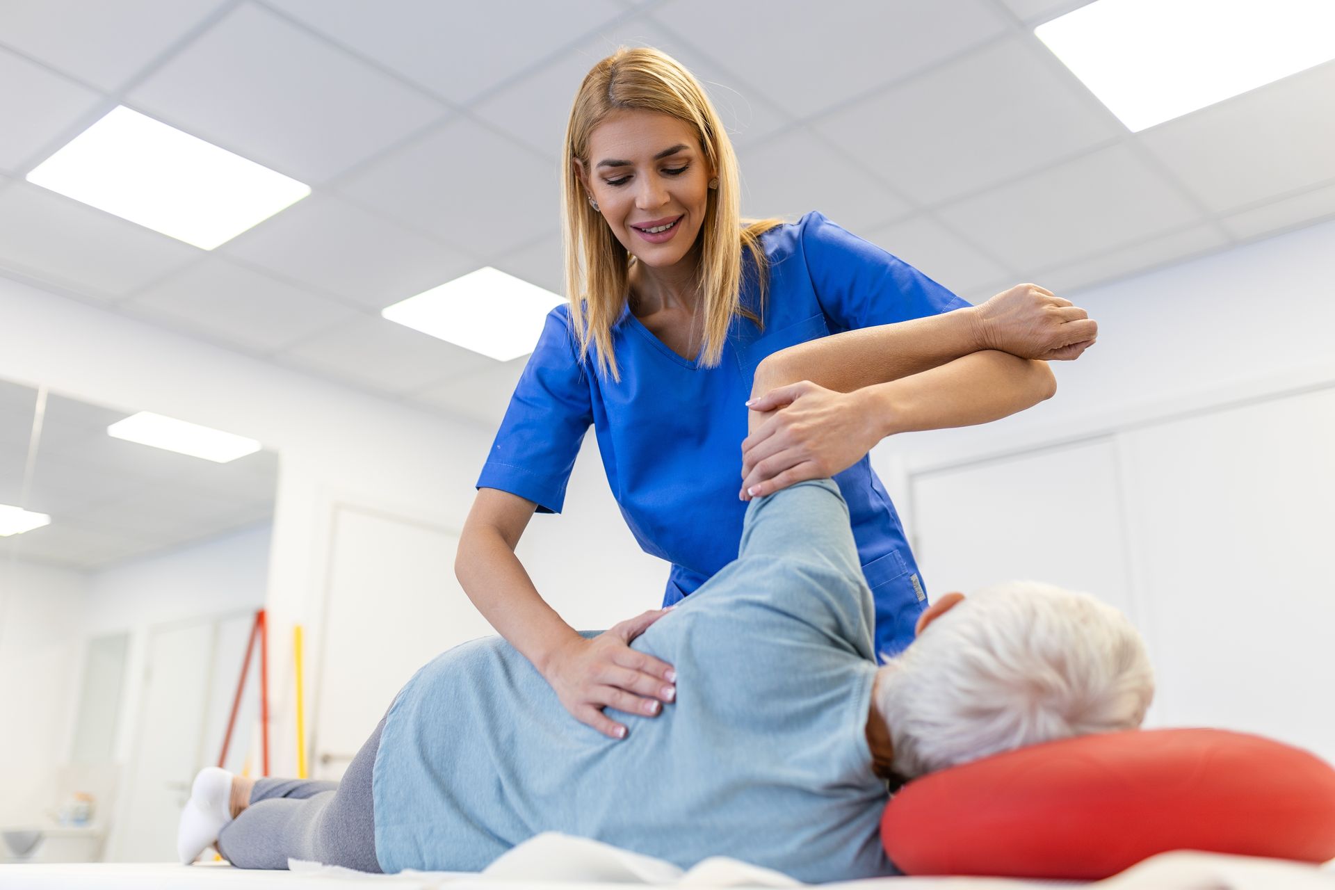 A nurse is helping an elderly woman stretch her arm.