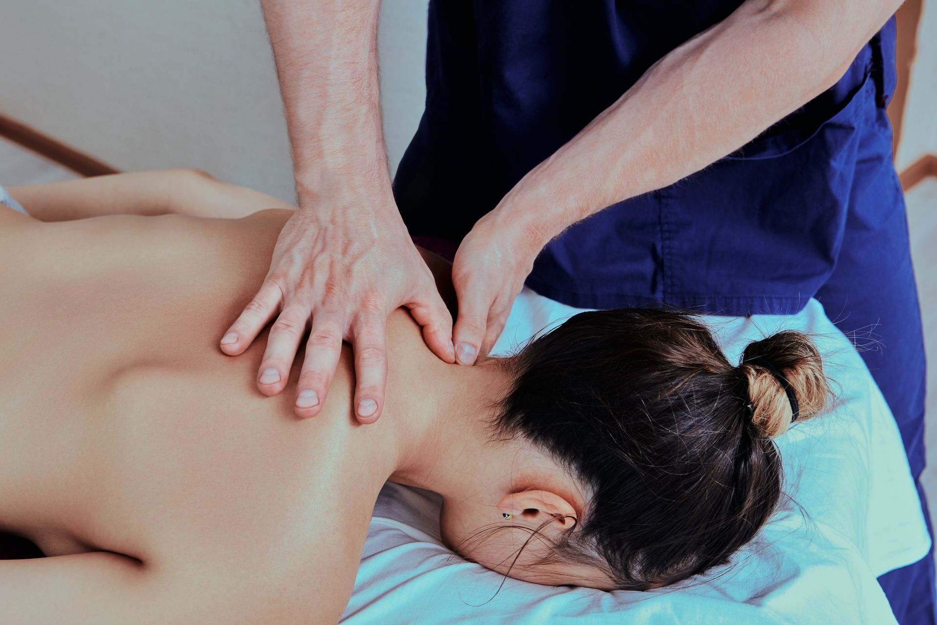 A woman is laying on a bed getting a massage from a man.