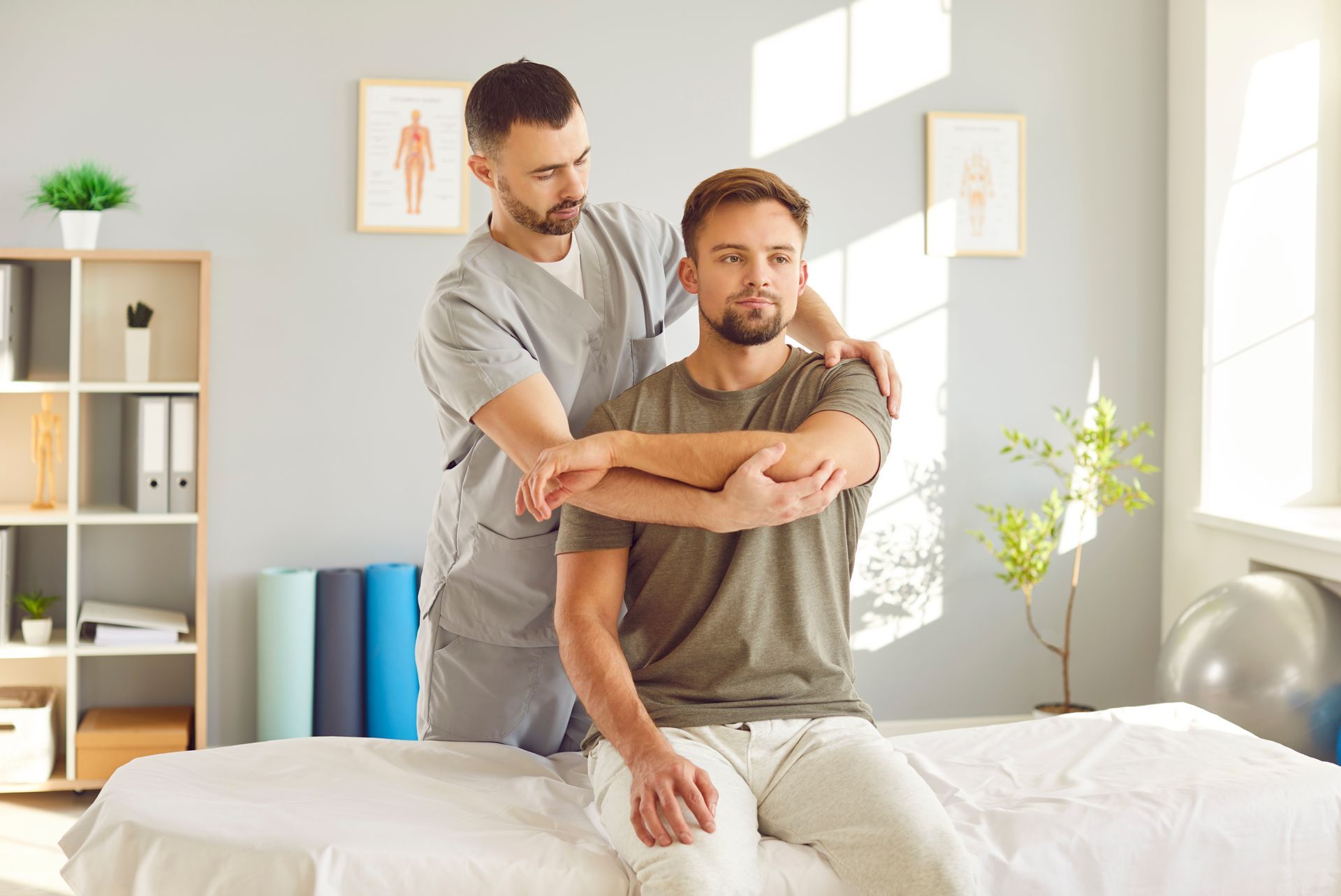 A man is sitting on a bed getting a massage from a doctor.