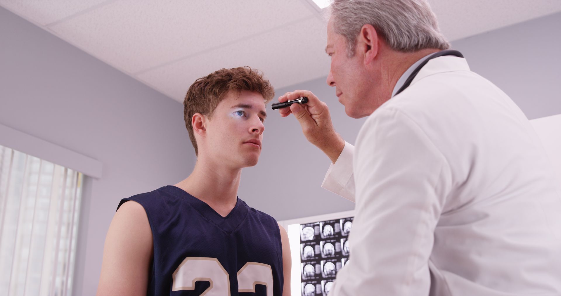 A doctor is examining a young man 's eye in a hospital.
