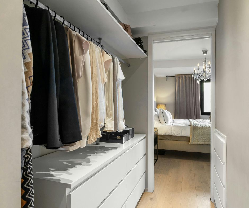 Walk-in closet with organised clothes and drawers.