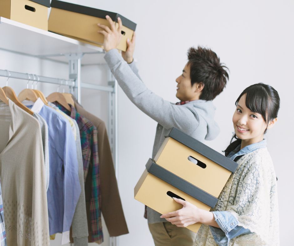 Two people packing clutter into boxes in a closet