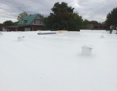 Un toit blanc avec une maison verte en arrière-plan.