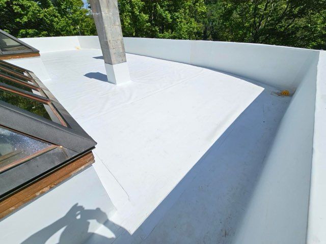 Toit plat blanc avec puits de lumière, bord incurvé et colonne de soutien. Journée ensoleillée.