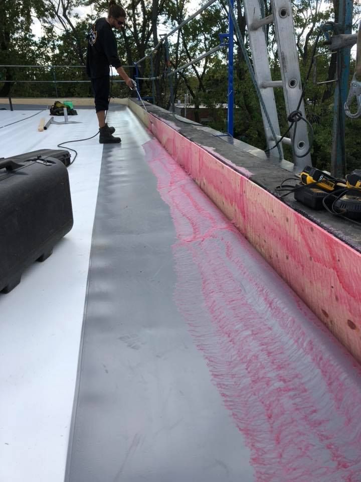 Un homme travaille sur un toit avec une échelle en arrière-plan.