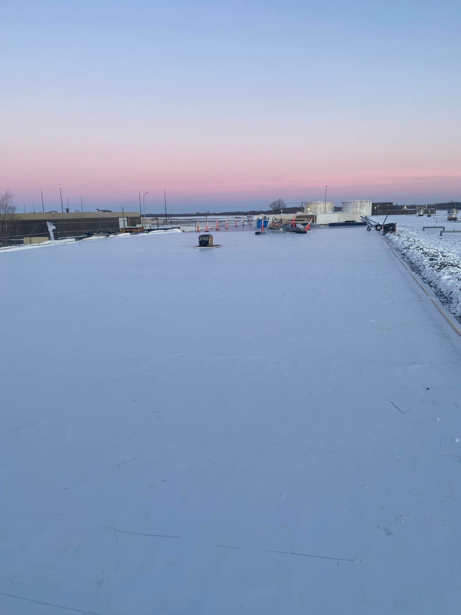 Un toit enneigé avec un coucher de soleil en arrière-plan