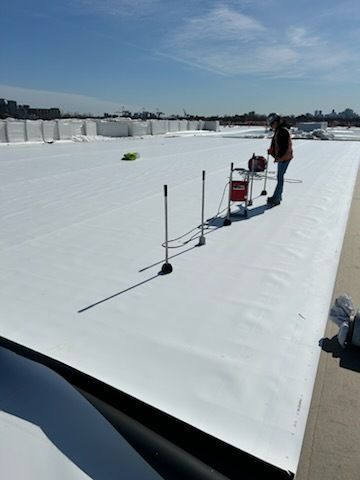 Couvreur sur un toit à membrane blanche avec des outils sous un ciel ensoleillé, se préparant au travail.
