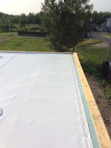 Une bâche blanche est posée sur un toit en bois.