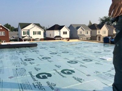 Une personne se tient sur un toit avec une feuille de pbr dessus