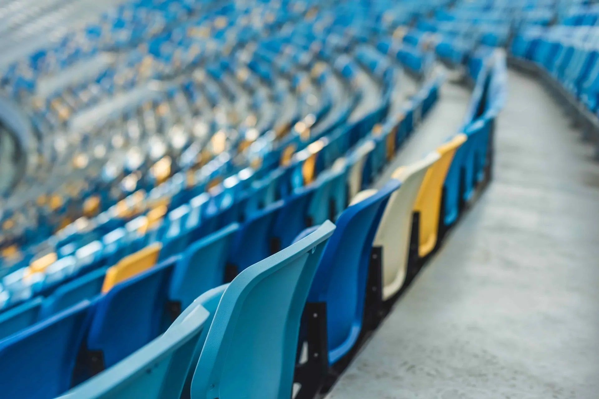 Rows of empty stadium seats in blue and yellow.