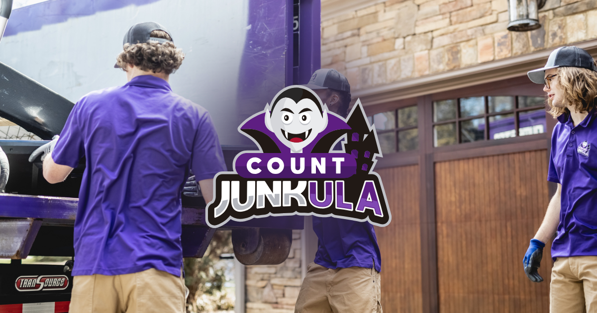 Two workers in purple shirts carrying a Count Junkula logo sign beside a truck and building