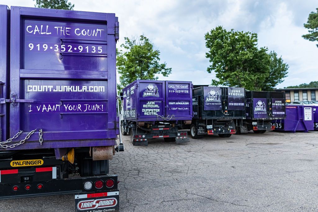 Purple Count Junkula dump trucks parked outdoors with company contact info.