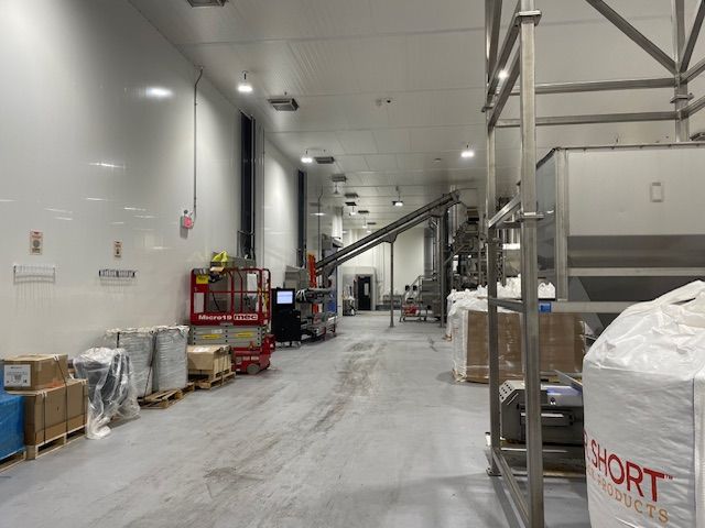 Factory interior with industrial equipment, white walls, and a long hallway.