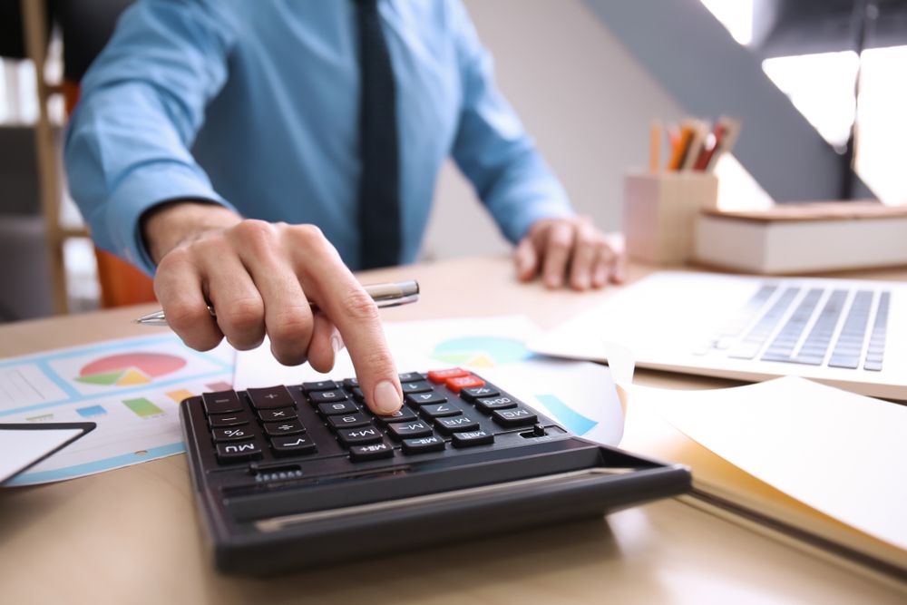 A man is using a calculator at a desk.