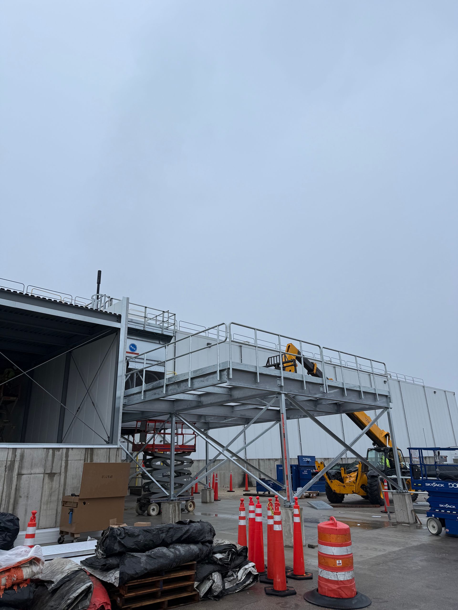 Construction site with scaffolding and a forklift under a cloudy sky.