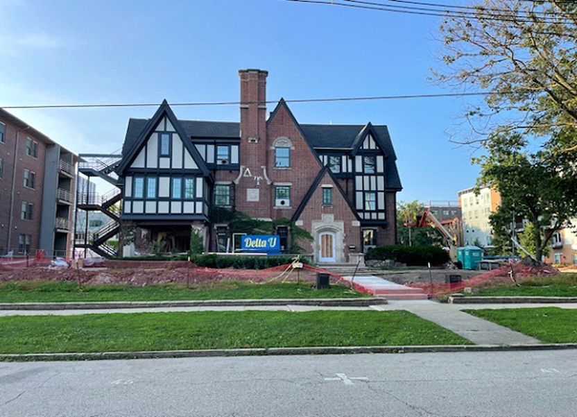 A large brick house with a black roof is being remodeled.