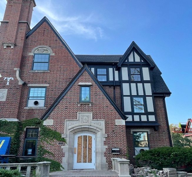 A large brick house with a black roof and white trim