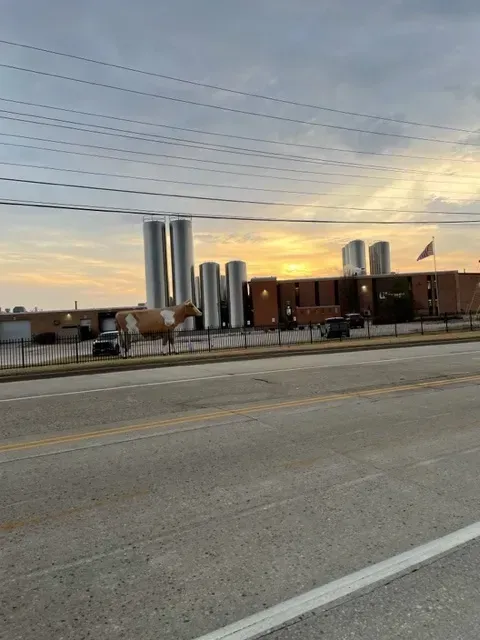 Industrial building with tall silos; cloudy sky at sunset.