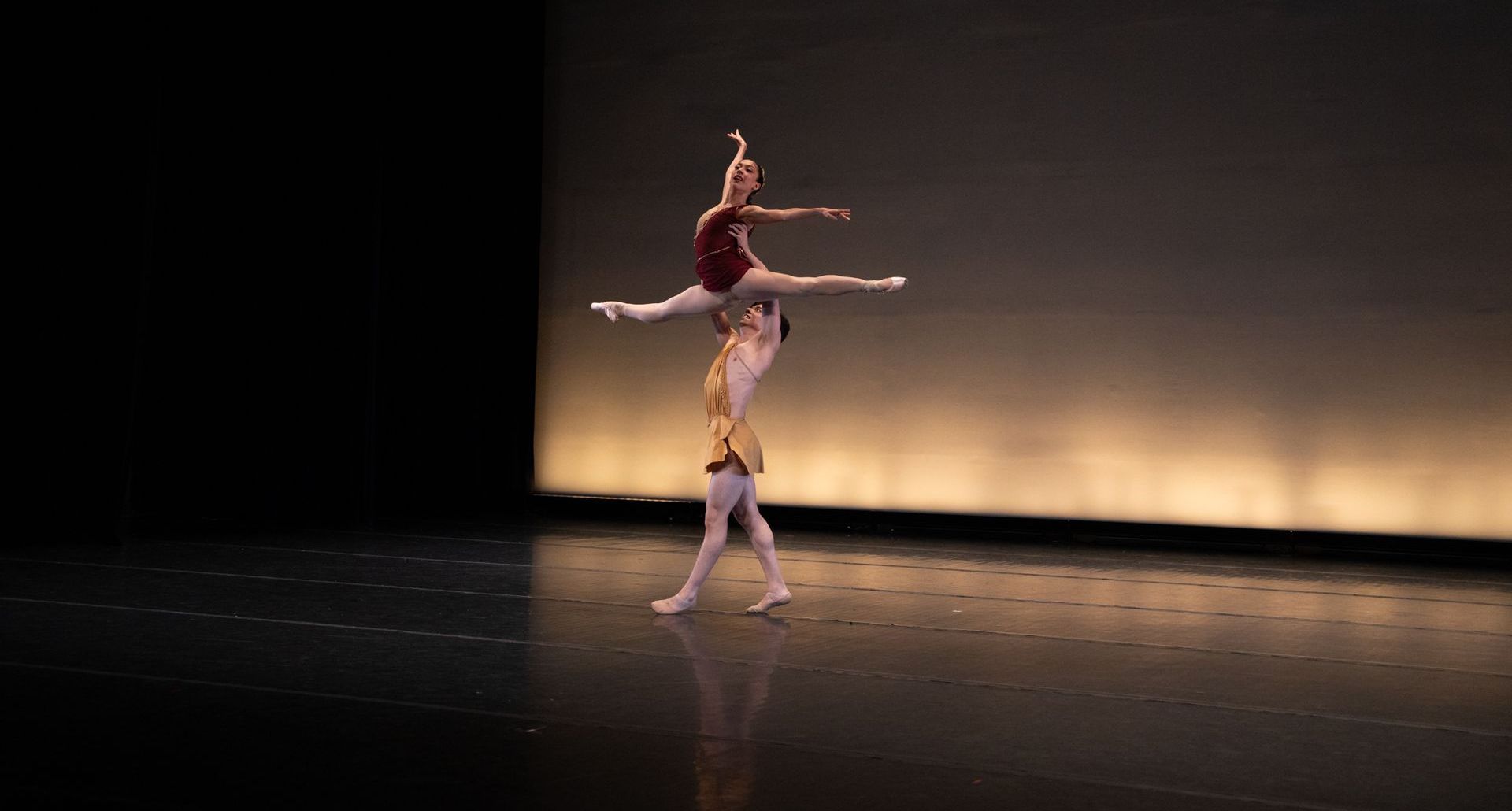 A couple of ballerinas are dancing on a stage.