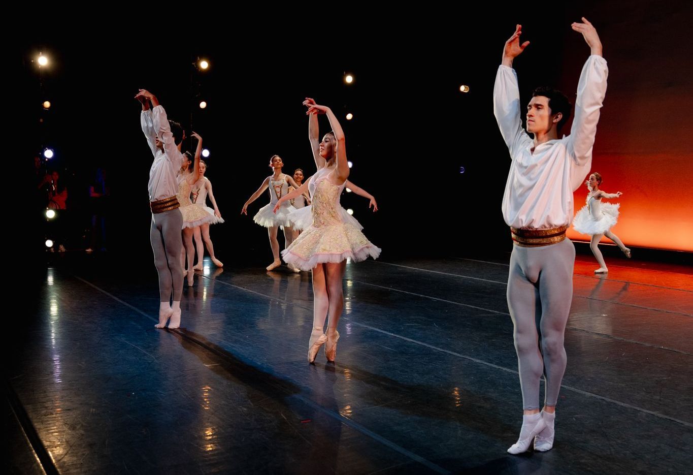 A group of ballet dancers are performing on a stage.