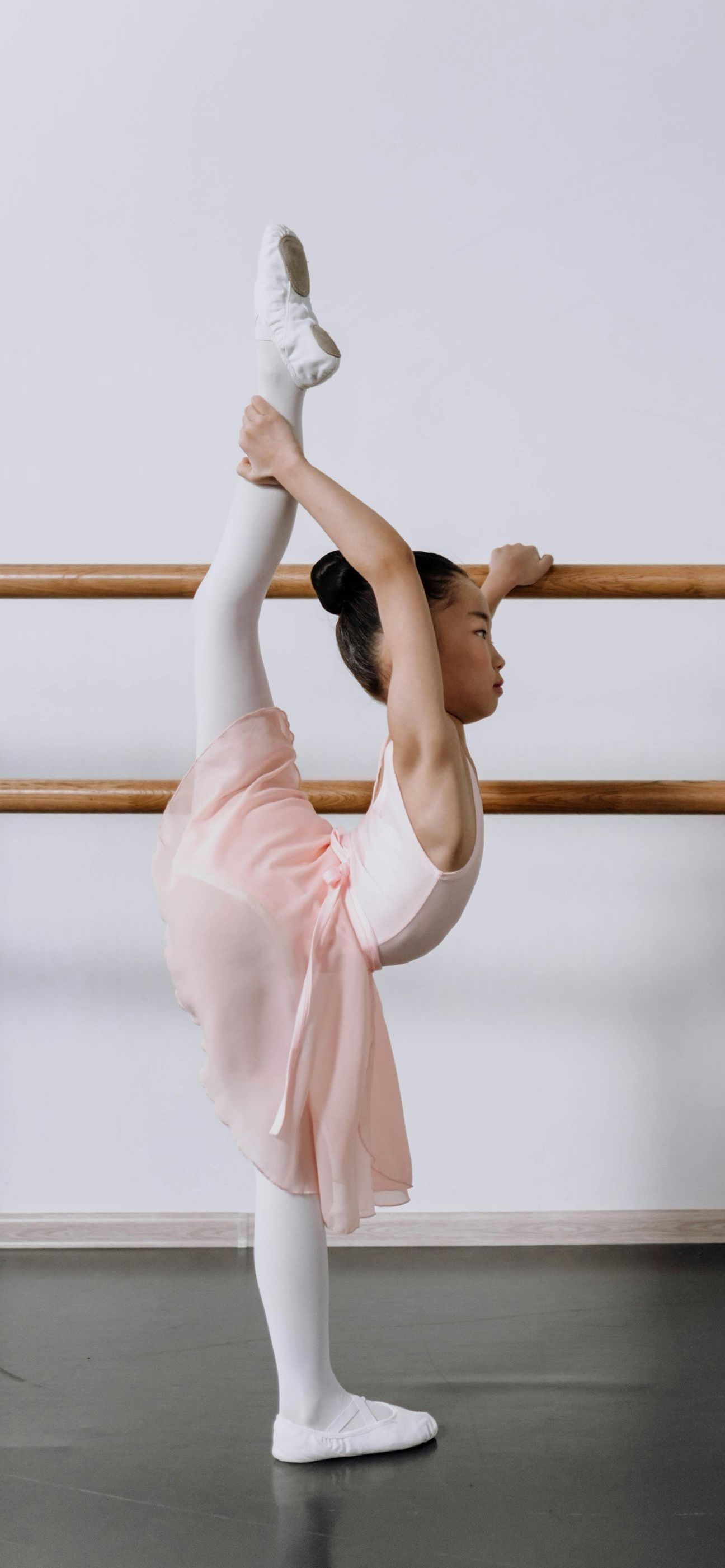 A young ballerina is doing a split in a dance studio.