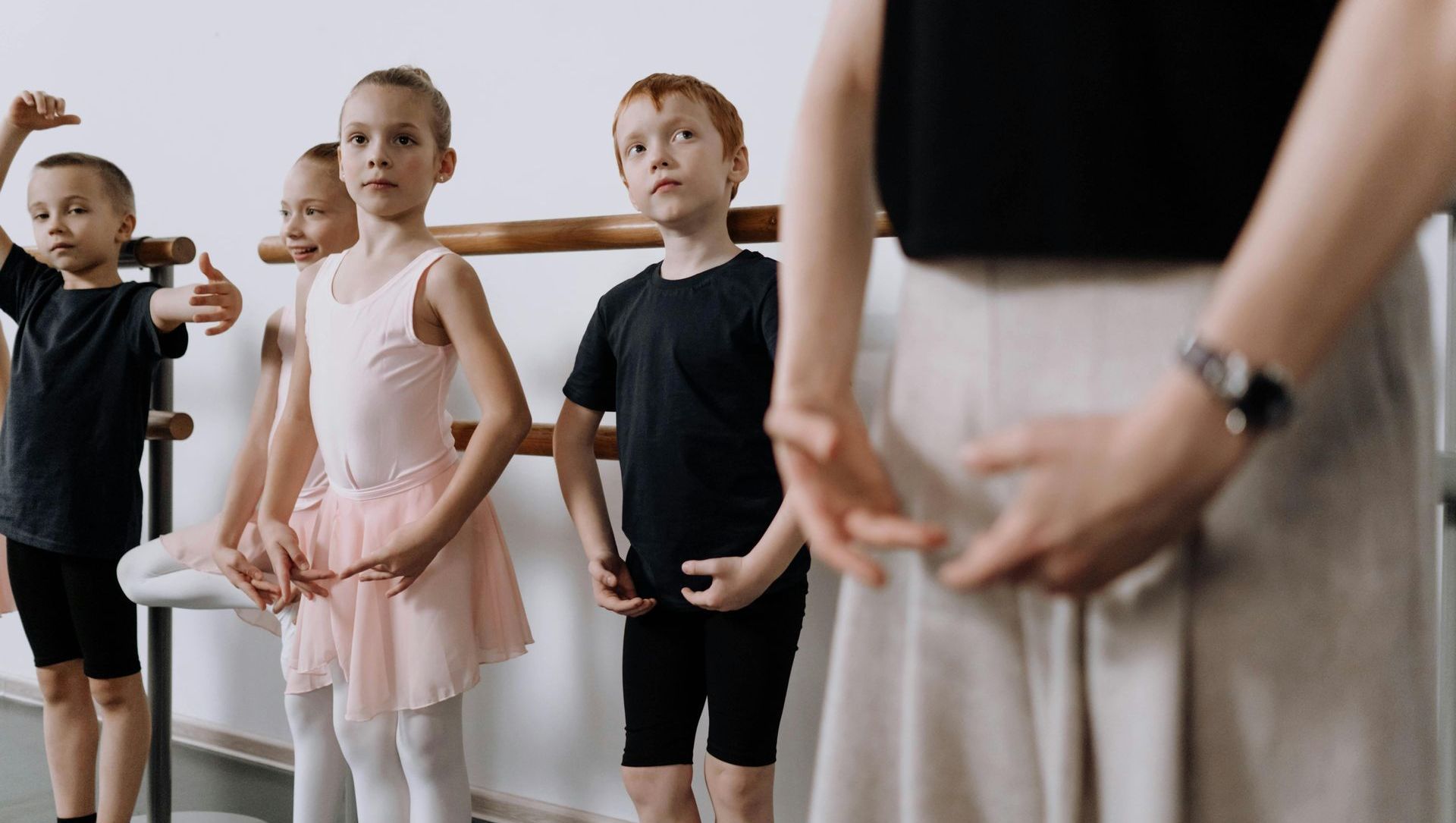 A group of young children are standing next to each other in a dance studio.