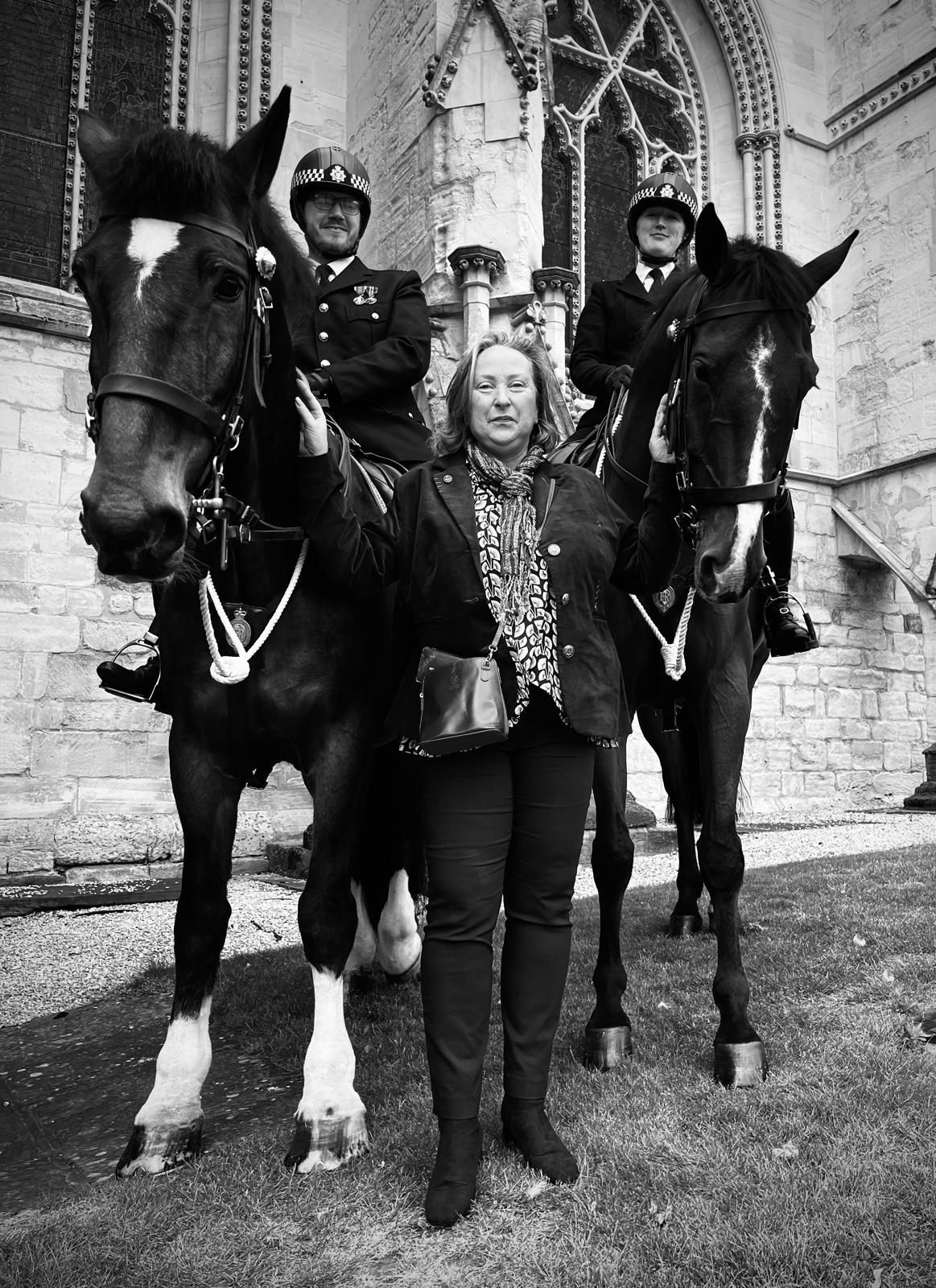 Man in kilt and woman in gown pose with mounted police in Liverpool.