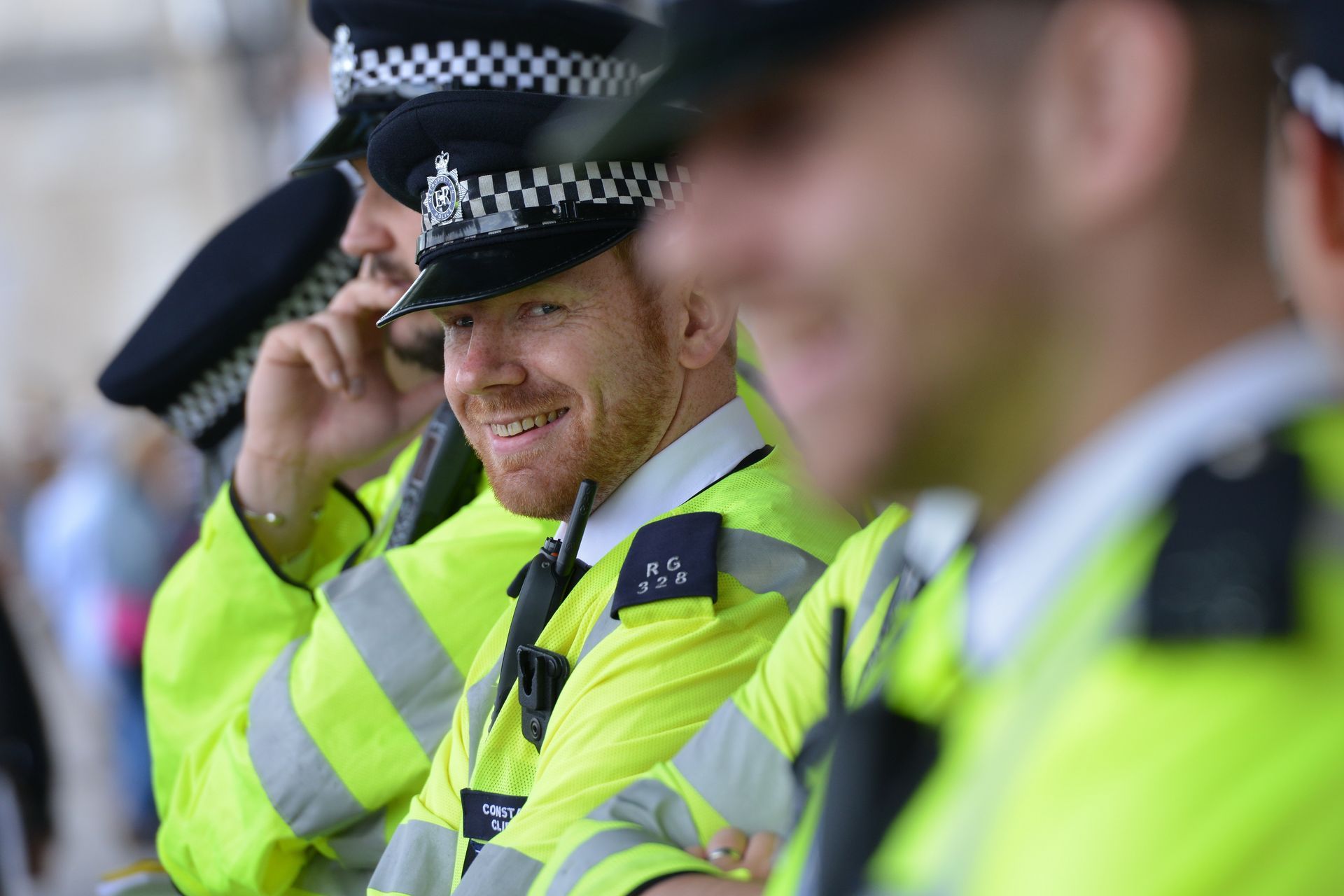 Smiling police officers in neon yellow vests and hats, standing close together outside.